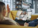 woman sitting on a sofa waving to her doctor on a telemedicine call network providers management