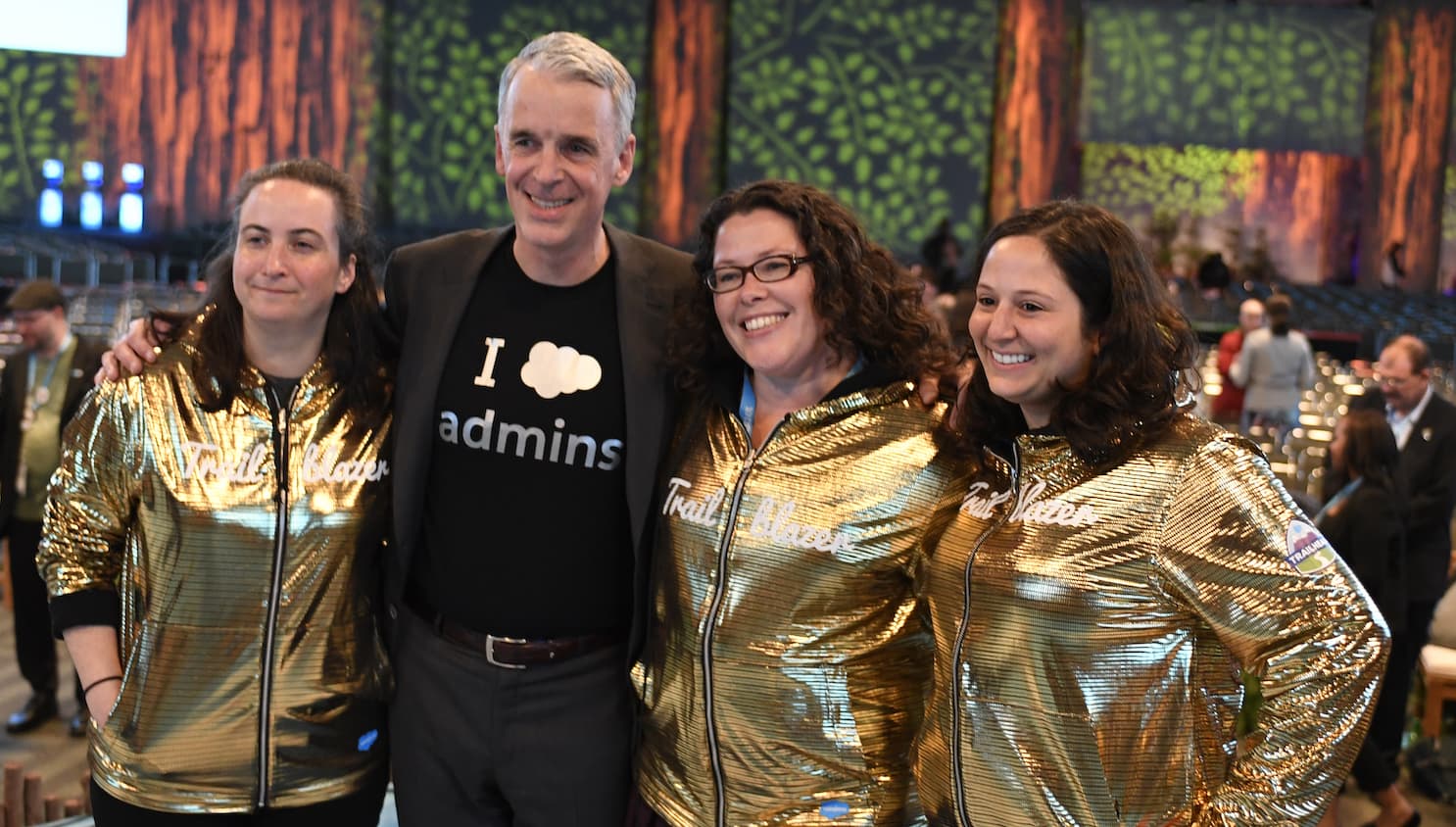 Salesforce co-founder Parker Harris posing next to three Trailblazers in golden hoodies
