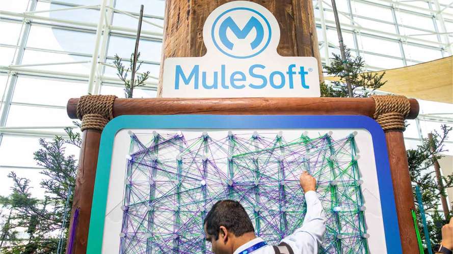 A man stands below a MuleSoft sign: What is MuleSoft
