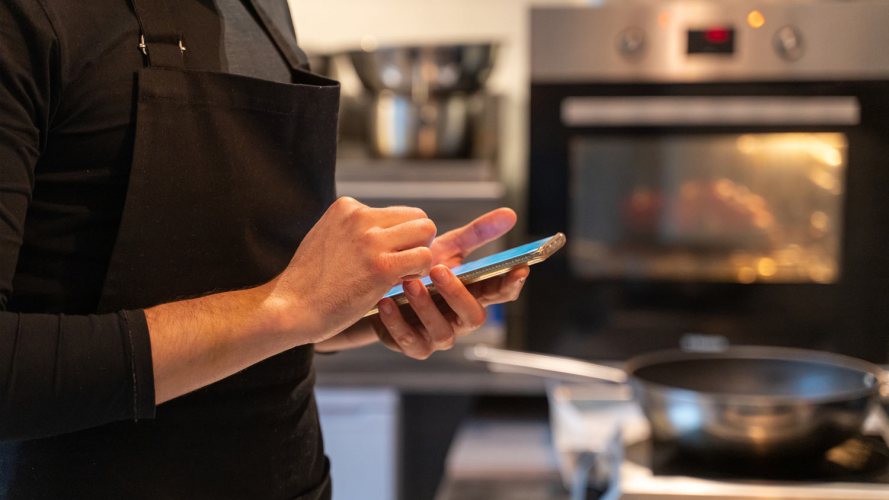 A restaurant worker uses a smartphone: digital dining.