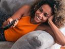 woman laying on couch with TV remote in her hand: subscription management