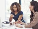 Two businesswomen in an office look at a tablet, exploring ways to use AI for wealth management