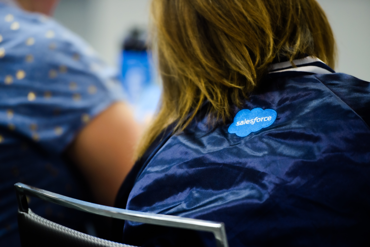 The back of a Trailblazer wearing a Salesforce branded jacket sat in a classroom setting.
