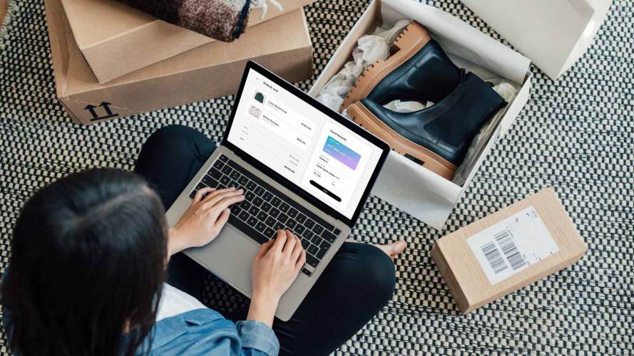 A shopper, surrounded by boxes of winter apparel, makes an online purchase using their laptop and credit card: holiday shopping season results