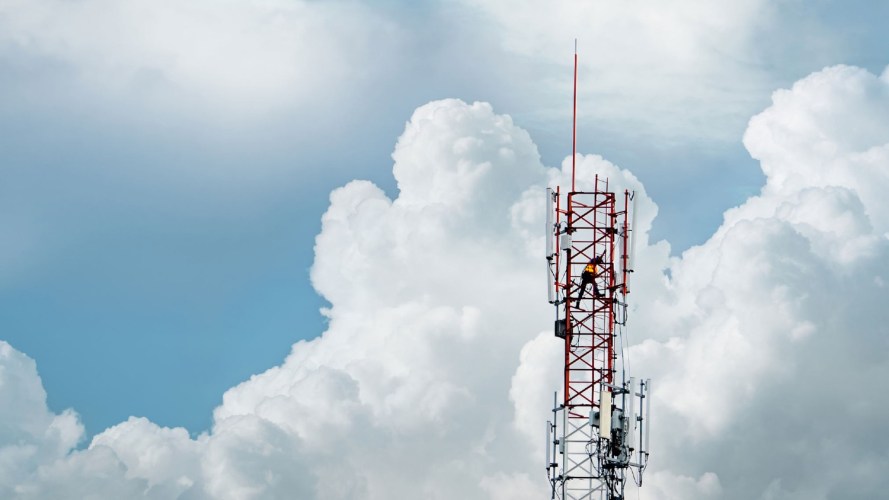 Photo of a worker on a cell phone tower: business support systems