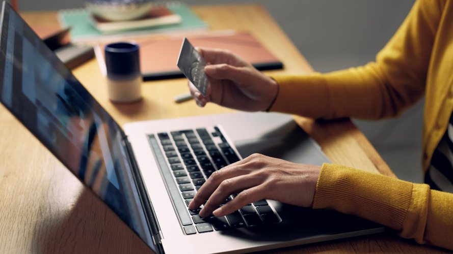 A person holding a credit card in front of a laptop computer. MVP ecommerce