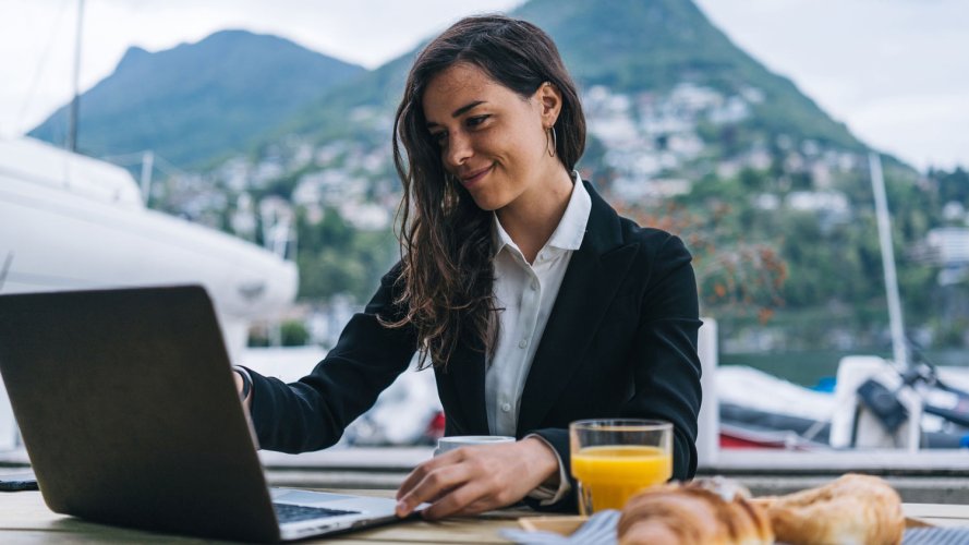 woman looking at laptop screen with a mountainside in her background: deepen employee engagement