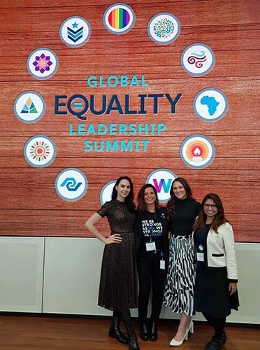 Photo of Suchi (right) with her colleagues in front of a sign that says "Global Equality Leadership Summit".