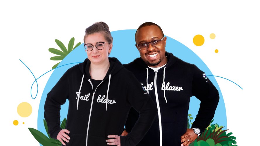 Two Salesforce Designers in Trailblazer hoodies confidently smiling against a vibrant blue background surrounded by foliage