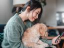 woman holding her dog and looking at her mobile phone: CRM insurance claims policy management