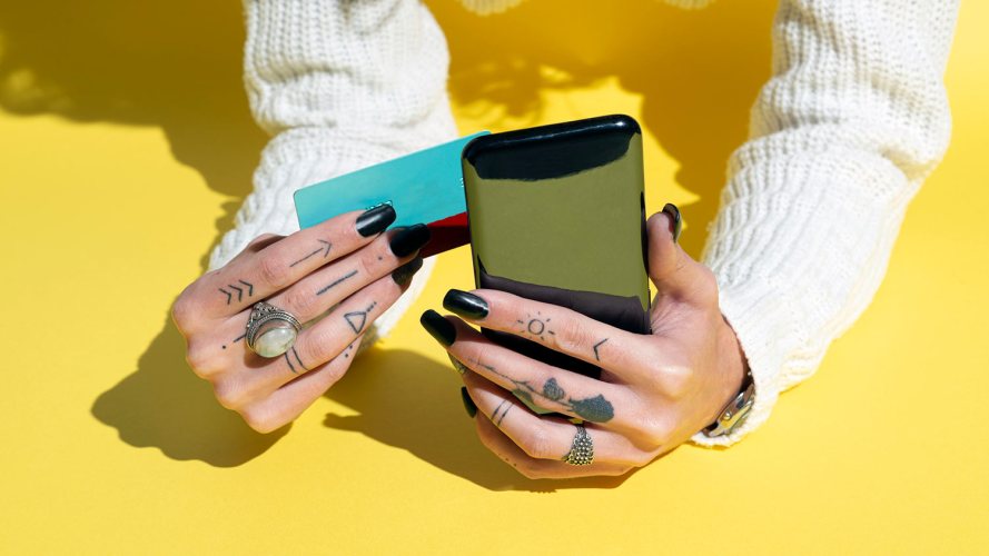 hands with tattooed fingers and black nail polish holding a smartphone and credit card: business success business growth
