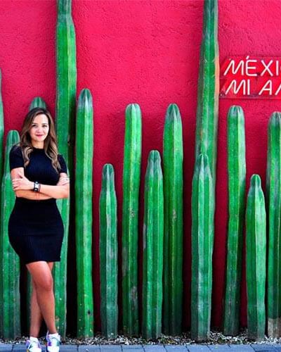 Photo of Elsa smiling while standing next to some cacti in Mexico