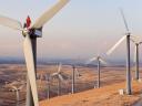 A worker stands atop a wind turbine. Fixing this equipment may require aftermarket parts.