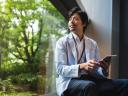 A man holds a tablet and looks out a window, perhaps pondering his partnership strategy.