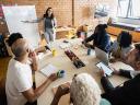 Woman presenting to a group of colleagues sitting at a table