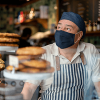 man wearing an apron and face mask at a cafe
