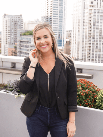 Kelly standing on the rooftop of a building, smiling and posing for a photo.