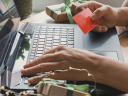 Image of woman typing credit card information on laptop / Keep Your Identity Safe This Season