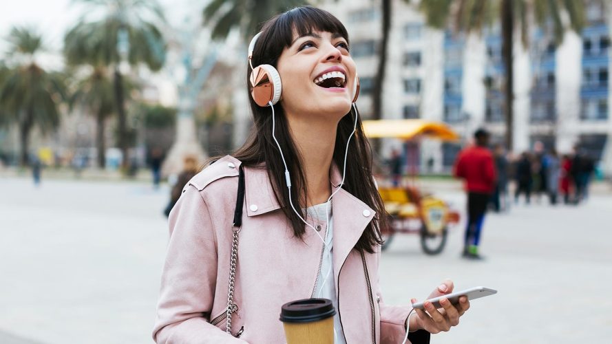 Person with headphones and a phone listening to the best business podcasts