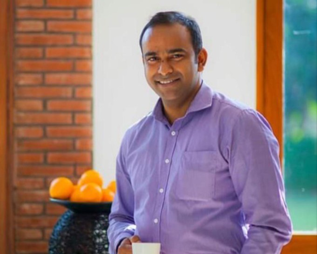 Photo of Manish Phalgunan smiling and holding a cup