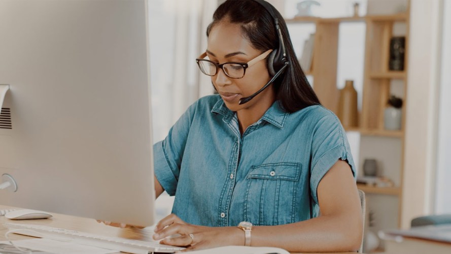 A woman with a headset takes a service call.