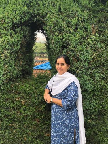 Photo of Kusuma standing next to some plants.