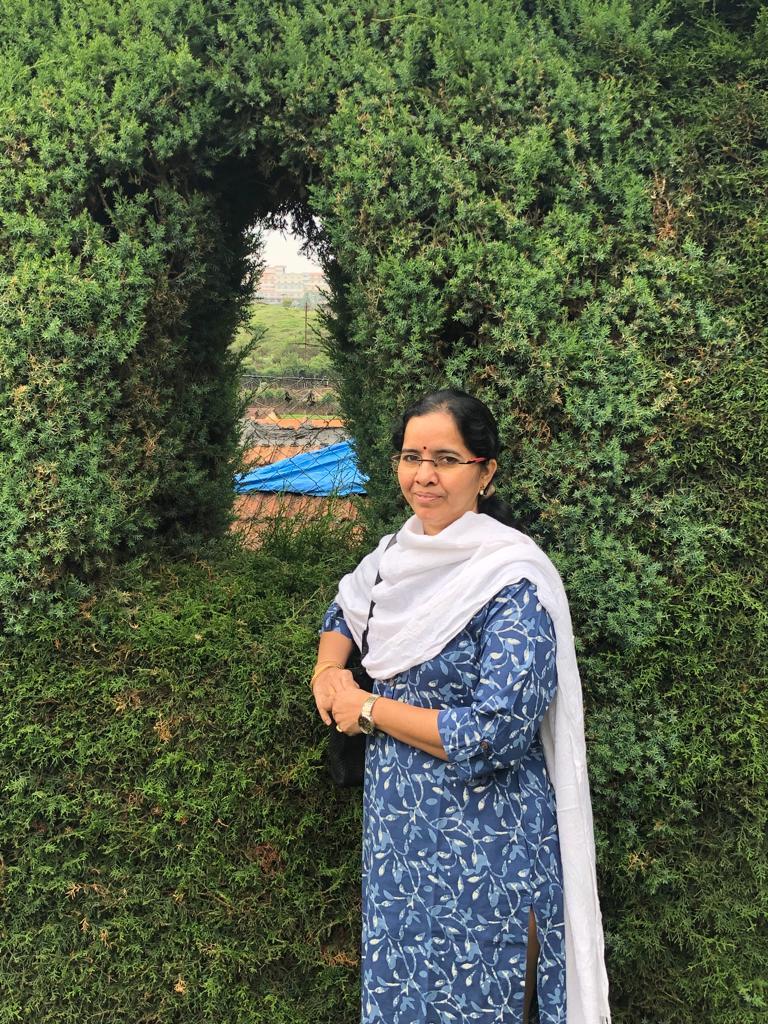 Photo of Kusuma standing next to some plants.