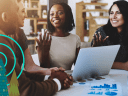 People talking while huddle around a laptop computer in a workplace.