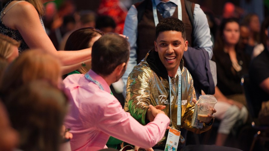 Photo of two people shaking hands at Salesforce Connections, one of which is wearing a gold Trailblazer hoodie