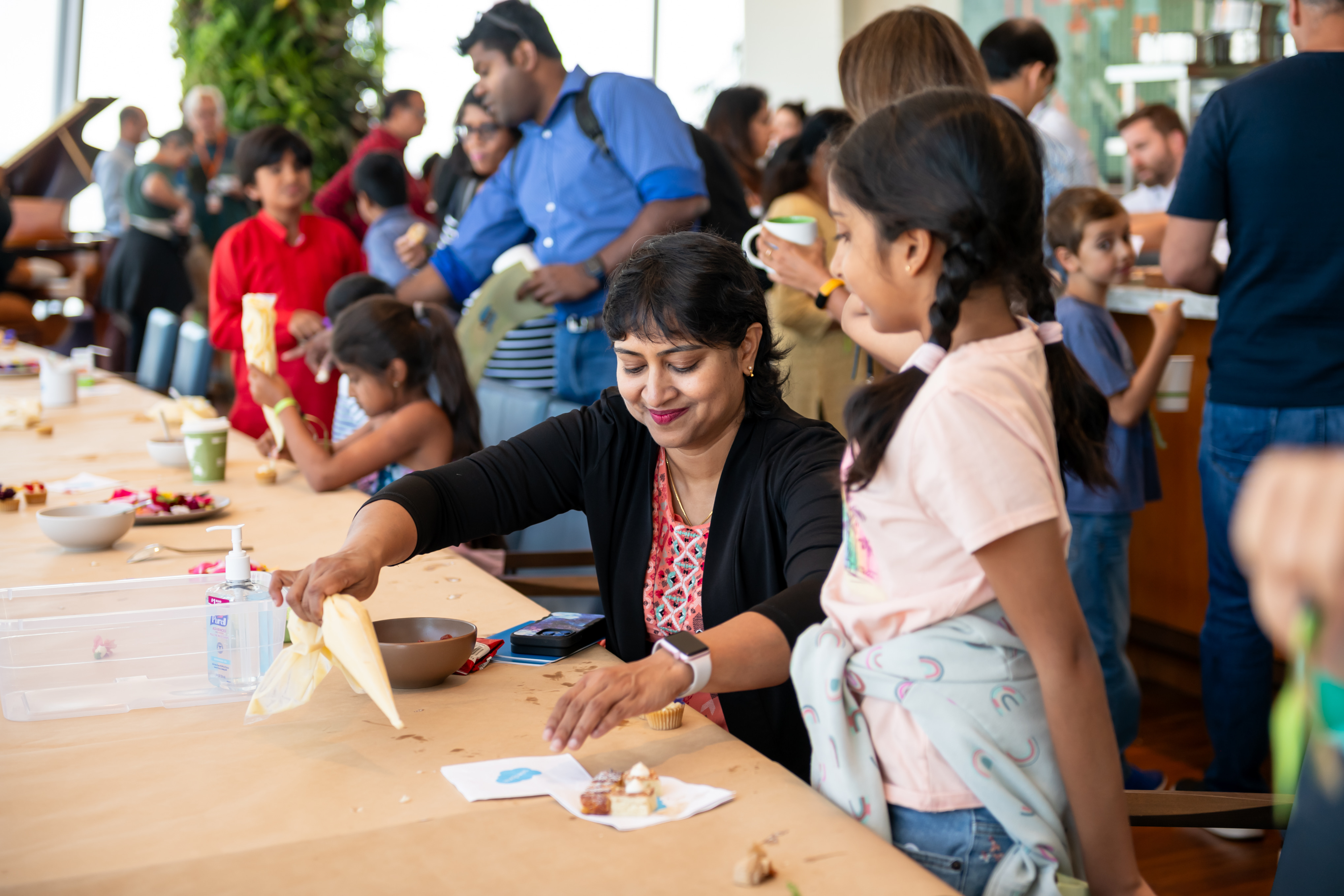 A Salesforce parent and her child enjoy cupcake decorating.