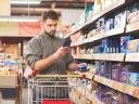 A grocery shopper uses their smartphone to compare the price of items online: retail pricing