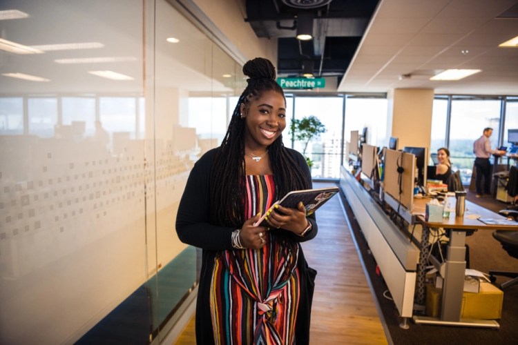 Salesforce employee, Denise Francis, Lead Product Designer at Salesforce, smiling while holding her laptop