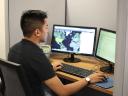 A man sitting at a desk and working on two computer monitors.