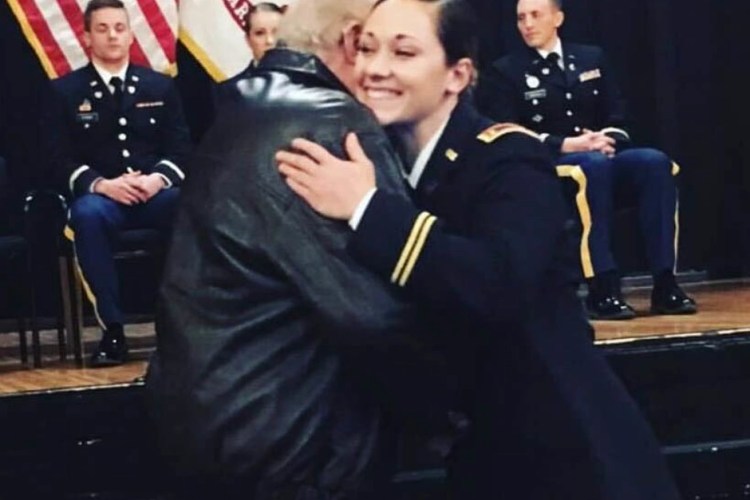A smiling Hanna embraces a man warmly during a formal ceremony.