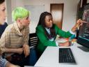 Photo of IT developers working to build AI apps. 3 people looking at a computer screen in an office setting.