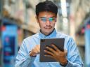 A man in glasses and a blue shirt uses a digital tablet for asset service management