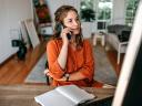 Young woman talking on smart phone at home office - stock photo.