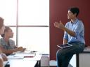 A teacher holding a tablet and speaking to a class, showing AI in education.