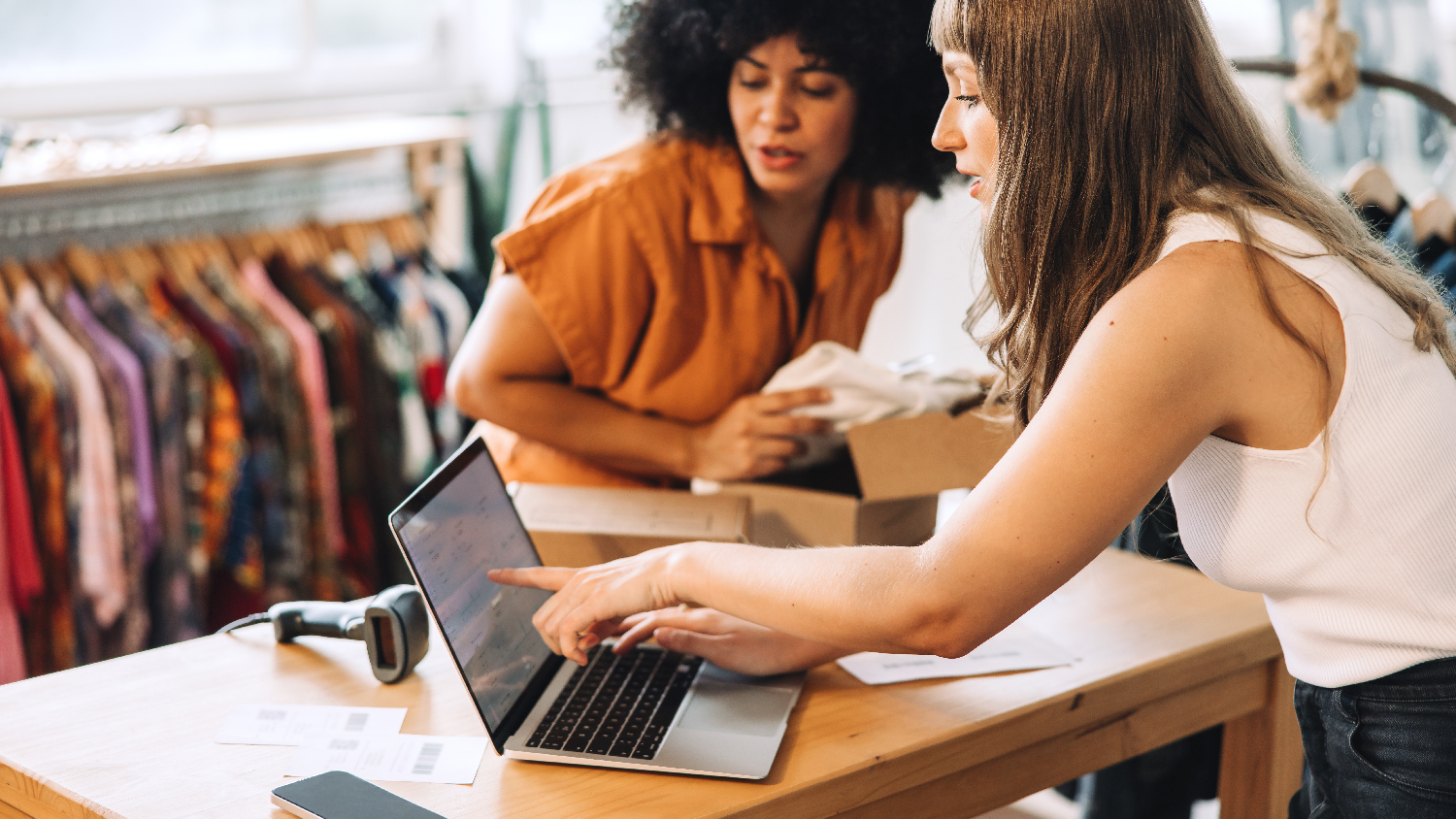 Two women using AI in a consumer goods company on a laptop.