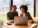 Two people discussing findings of AI-powered CRM research in front of computer.