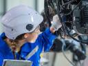 A female technician in a field service career uses her technical expertise to do preventative maintenance on a piece of equipment