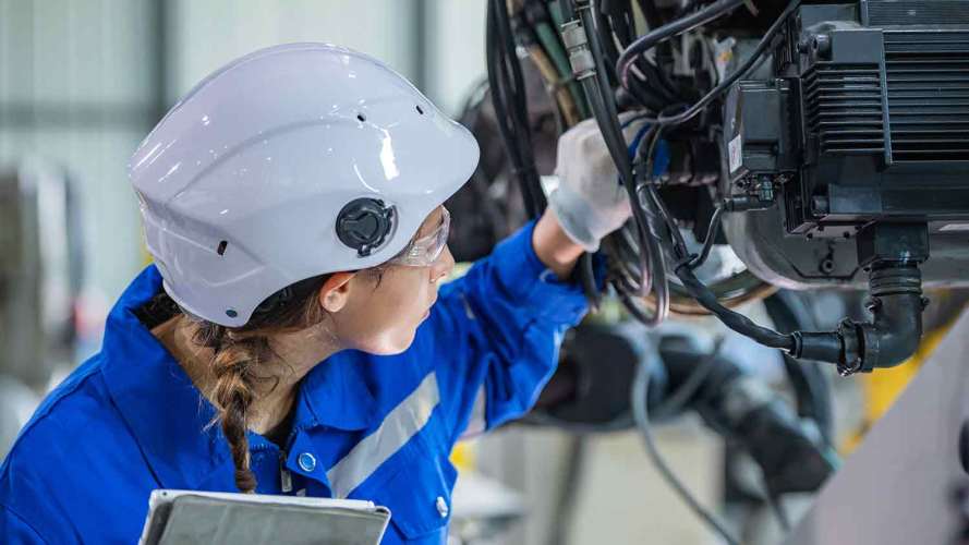 A female technician in a field service career uses her technical expertise to do preventative maintenance on a piece of equipment