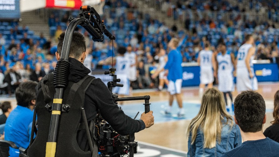 Photo of a cameraman working during a college basketball game / sports marketing