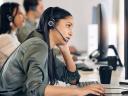 A call center agent sits at their desk, looking exhausted and overwhelmed.