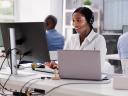A Black woman in a call center uses dispatch management to schedule the right field service technician