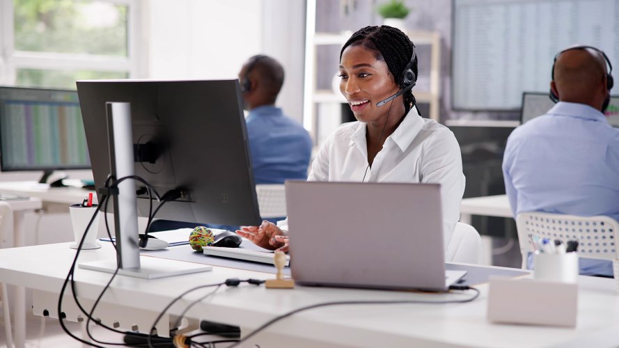 A Black woman in a call center uses dispatch management to schedule the right field service technician