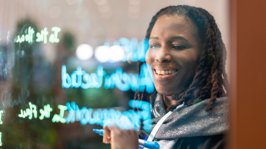 Woman writing "Well-Architected Framework" on a lightboard.