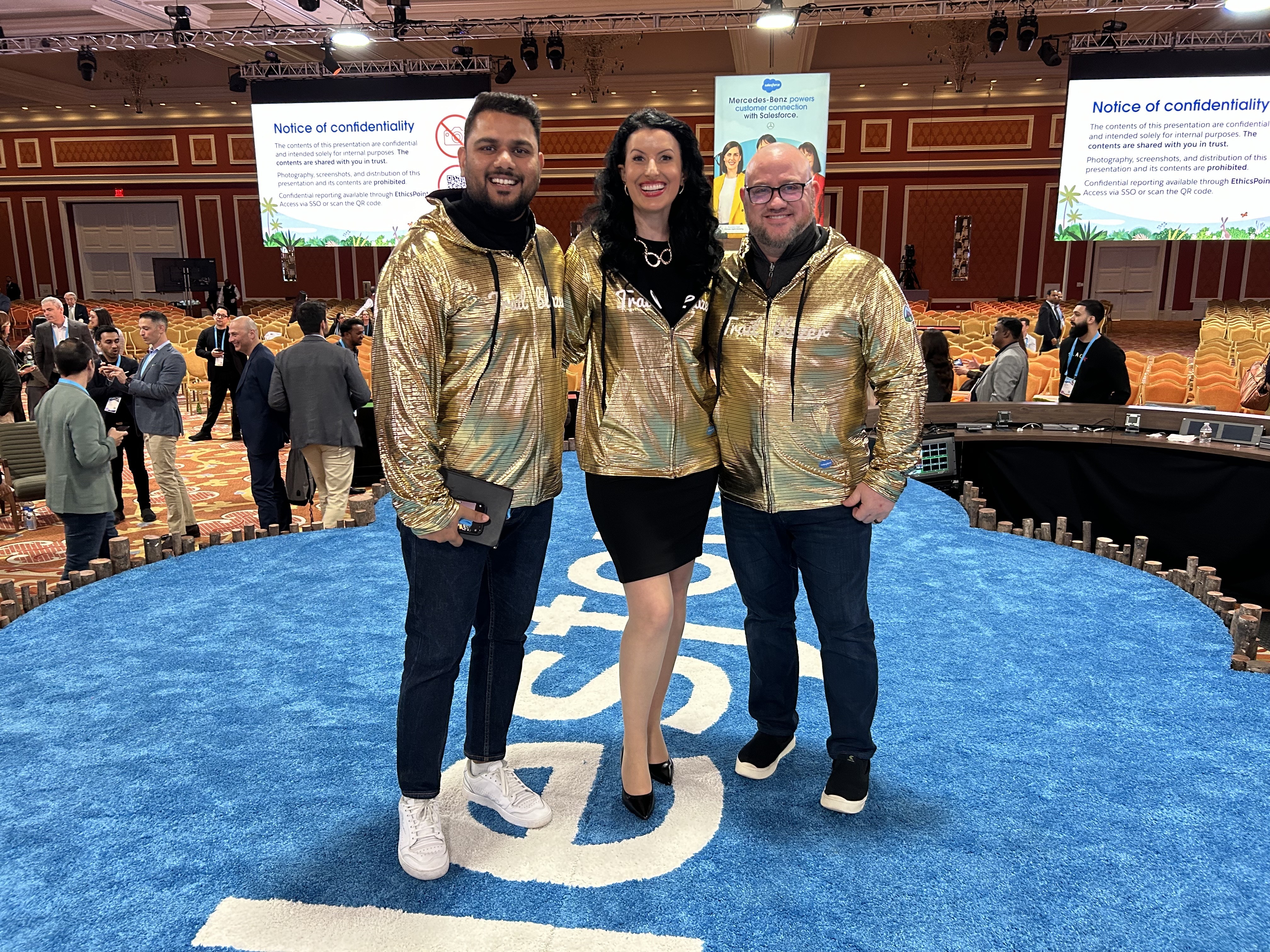 Three people wearing gold sweaters that say "Trailblazer" at a Salesforce event.