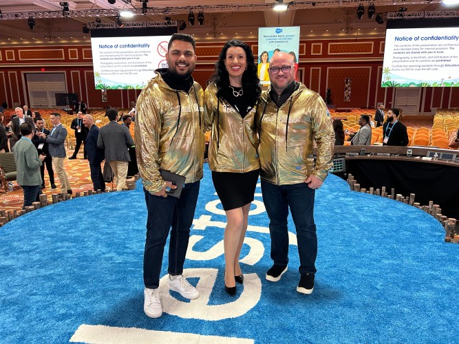 Three people wearing gold sweaters that say "Trailblazer" at a Salesforce event.