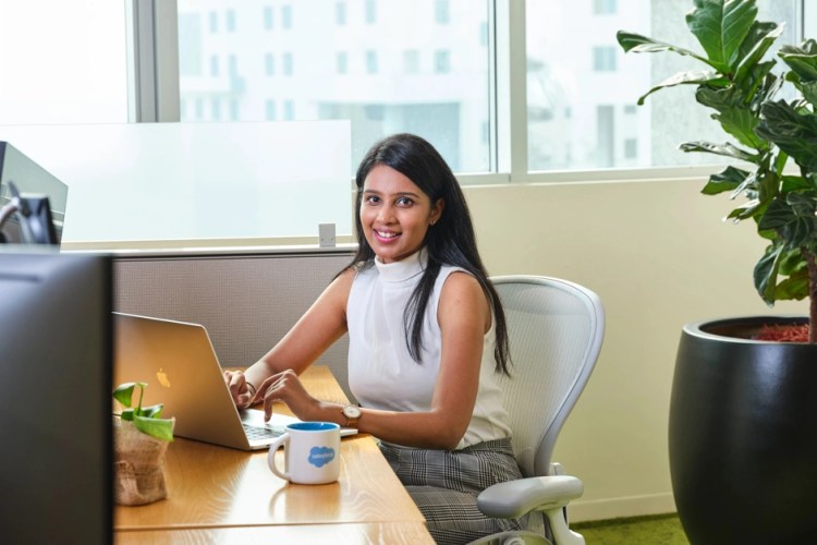 Salesforce India employee sitting at her desktop and smiling.